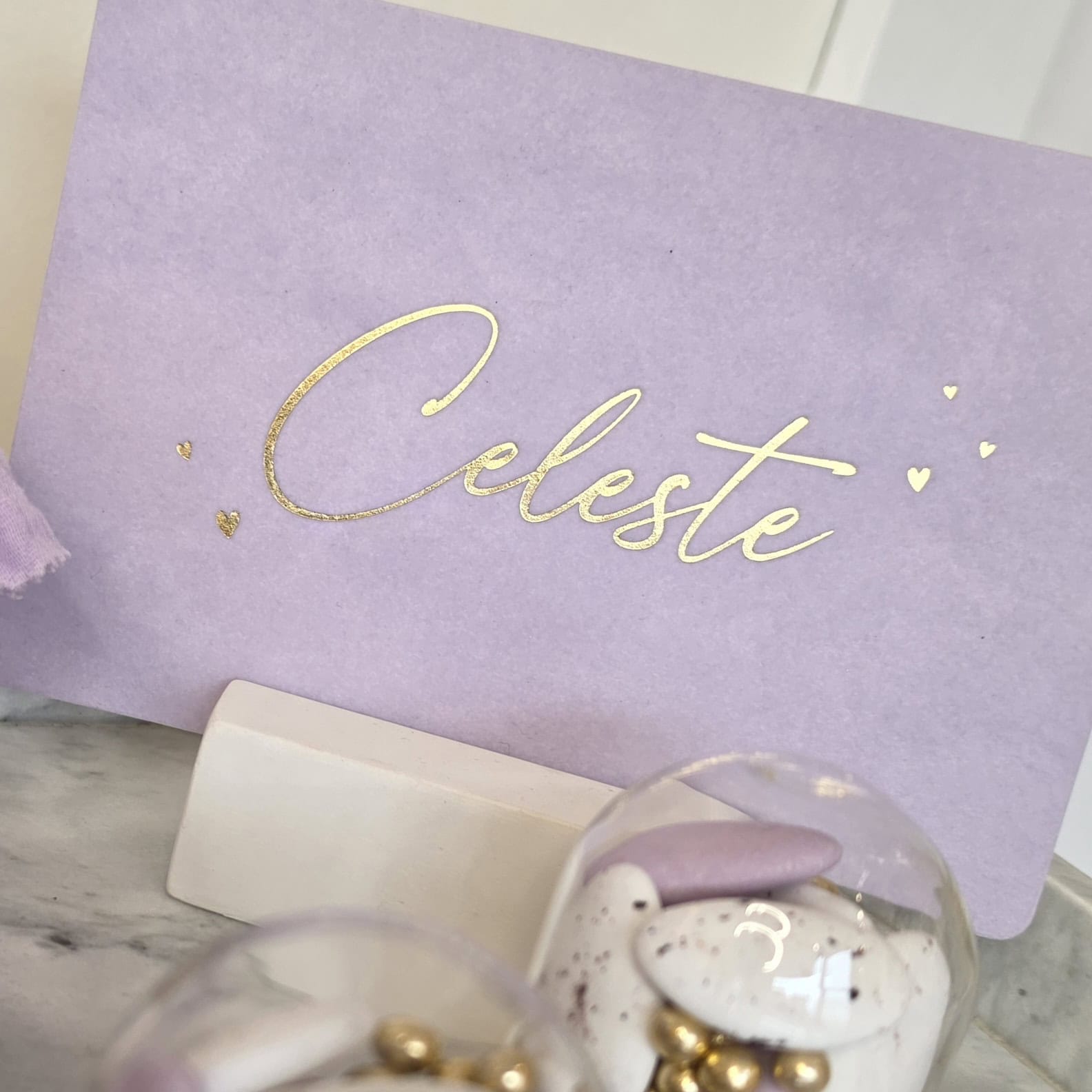 Lila kaart met de naam Celeste en gouden hartjes.